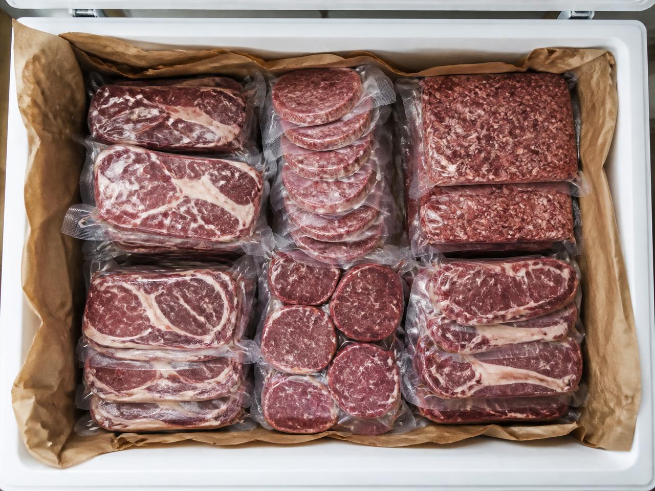 Vacuum-sealed steaks, patties and ground beef packed neatly in a paper-lined freezer box